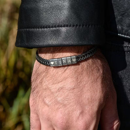 Black personalized braided bracelet with engraved name beads worn on a man's wrist