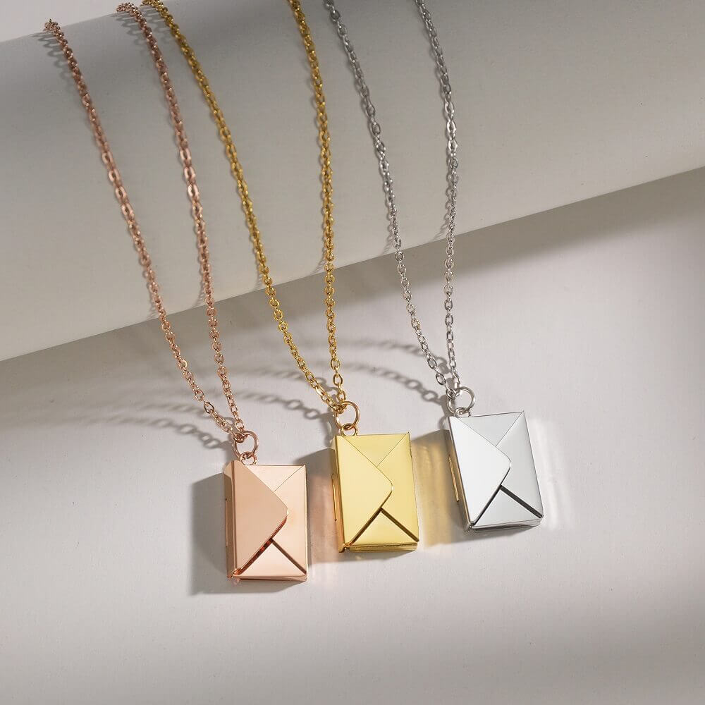 Three personalized envelope necklaces in silver, gold, and rose gold presented in a premium gift box.